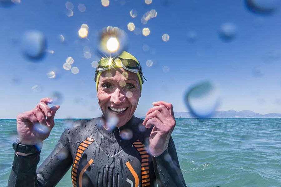 Atleta sorridente in muta e cuffia in mare