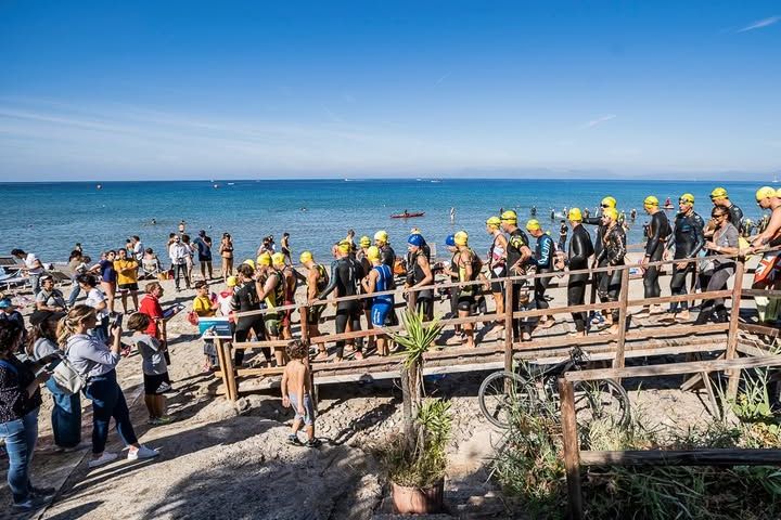 Atleti con cuffie gialle in fila verso il mare alla 30 Eggs